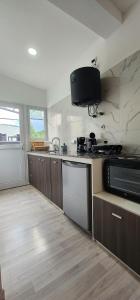a kitchen with a sink and a stove and a microwave at Sunset Esquel in Esquel