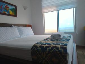 1 dormitorio con 1 cama y 2 ventanas grandes en La Bocana de Quiximies Hotel, en Cojimíes