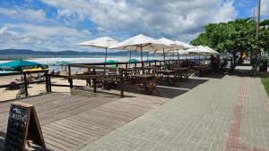 a boardwalk with tables and umbrellas on the beach at Apartamento praia centro itapema in Itapema