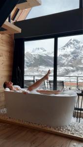 una mujer tumbada en una bañera con vistas a las montañas en Kazbegi Story, en Kazbegi