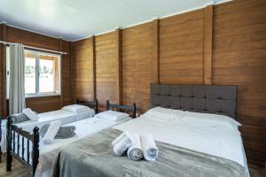 two beds in a room with wooden walls at Celeiro da Lagoa - Chalé confortável em meia à Natureza A apenas 8 km de distância da praia central de Balneário Picarras e a 15 Parque Beto Carrero World in Piçarras