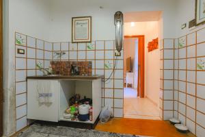 een keuken met een betegelde muur met een aanrecht en een kamer bij Casetta centro storico in Zagarolo