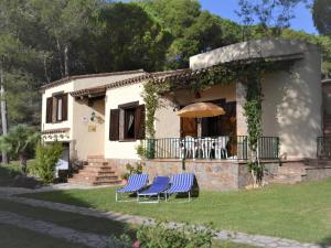 ein Haus mit zwei blauen Stühlen und einem Regenschirm in der Unterkunft Casa con Gran Jardín Privado y Piscina Comunitaria en Torroella de Montgrí - ES-323-44 in L'Estartit