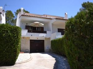 une maison blanche avec un garage et un parasol dans l'établissement Casa L'Estartit, 3 dormitorios, 6 personas - ES-323-54, à L'Estartit