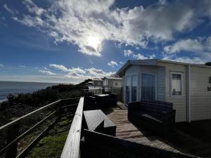 a house on a wooden deck next to the ocean at 6 Berth Caravan With Stunning Sea Views And Decking To Relax On, Ref 32048az in Lowestoft