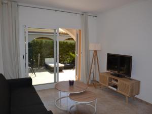 ein Wohnzimmer mit einer Couch, einem Fernseher und einem Tisch in der Unterkunft ¡Casa encantadora con piscina y cerca de la playa en L'Estartit! - ES-323-55 in L'Estartit