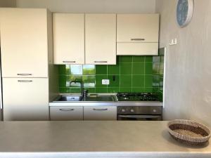 una cocina con armarios blancos y azulejos verdes en Punta Est Giardino e Vista Mare, en Capo Coda Cavallo