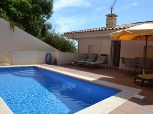 a swimming pool with chairs and an umbrella next to a house at Casa Mediterranea - L'Estartit, Roca Maura - ES-323-70 in L'Estartit