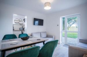 une salle à manger avec une table et des chaises vertes dans l'établissement Gower Hideaway - 3 Bed Apartment - Ocean Breeze, à Port Eynon