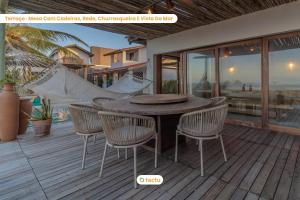 un patio con una mesa de madera y sillas en una terraza en Casa Desert Point com piscina vista mar por Tactu, en Taíba