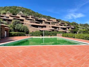 a building with a swimming pool in the middle of a courtyard at Punta Est Giardino e Vista Mare in Capo Coda Cavallo