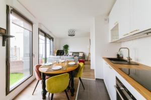 a kitchen and living room with a wooden table and yellow chairs at Le Jardinet - parking gratuit dans la résidence - Jardin ensoleillé in Fontainebleau