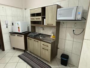 a small kitchen with a sink and a microwave at Apartamento com mobília nova 201! in Francisco Beltrão +3 photos