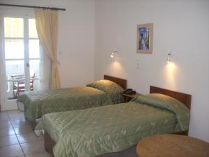 a hotel room with two beds and a balcony at Vassiliki Studios in Andros