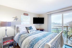 a white bedroom with a bed and a balcony at Breakwater Inn - Mastodon Cottage #G in Grayland