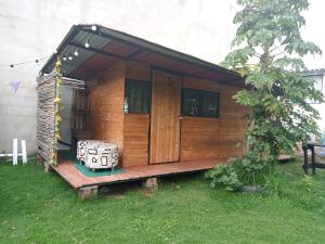a small wooden cabin with a porch in the grass at CASA BAHAREQUE HOSPEDAJE in Monguí