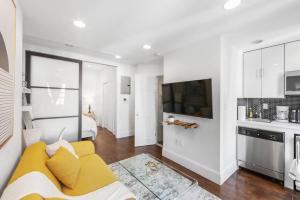 a living room with a yellow couch and a kitchen at 69-5B I Stylish Lower East Side 1BR Apt BRAND NEW in New York