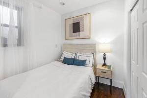 een witte slaapkamer met een bed met blauwe kussens bij 69-5B I Stylish Lower East Side 1BR Apt BRAND NEW in New York