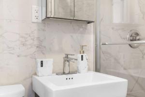 een witte badkamer met een wastafel en een toilet bij 69-5B I Stylish Lower East Side 1BR Apt BRAND NEW in New York