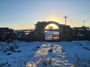 a stone wall in a snow covered field with the sunset at Private annex to Victorian villa, with kitchen and Free parking in Todmorden