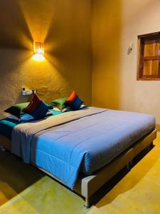 a bedroom with a bed with blue sheets and colorful pillows at My Village in Tissamaharama