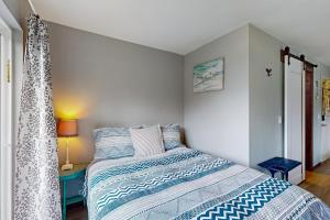 a bedroom with a bed with a blue and white comforter at Breakwater Inn - Bulfinch Condo #5 in Grayland