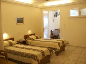 a hotel room with two beds and a chair at Vassiliki Studios in Andros