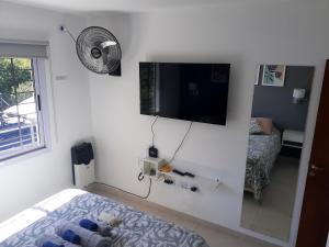 Habitación blanca con TV en la pared en Departamento Nuevo! 2 Dormitorios LA FALDA CORDOBA en La Falda