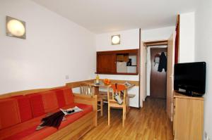 a living room with a red couch and a table at Résidence Odalys Le Hameau du Borsat in Tignes