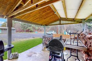 d'une terrasse couverte avec un barbecue et une table. dans l'établissement Breakwater Inn - Josie Dyas Cottage #H, à Grayland