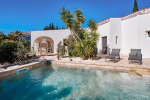 een zwembad met twee stoelen en een huis bij Do Jardim in Carvoeiro