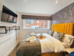a bedroom with a large bed with a yellow headboard at Cobblestone Studio in Cheltenham
