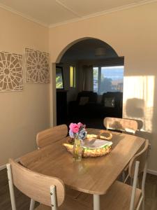 a dining room table with a vase of flowers on it at The Homestead - cosy 3 bedroom house in Rotorua