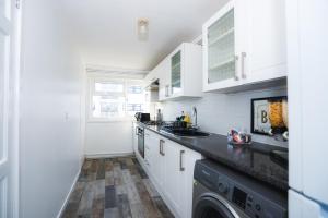 cocina con armarios blancos y lavavajillas en 1 Bed Flat Tottenham Hale N17 en Londres