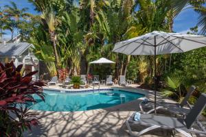 uma piscina com guarda-sol e cadeiras em Paradise Inn - Adult Exclusive em Key West