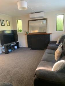 a living room with a couch and a flat screen tv at The Homestead - cosy 3 bedroom house in Rotorua