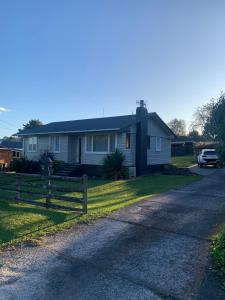 a house with a fence on the side of a road at The Homestead - cosy 3 bedroom house in Rotorua