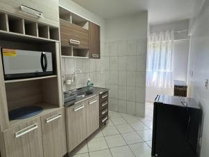 eine Küche mit einer Spüle und einer Mikrowelle in der Unterkunft Apartamento com mobília nova 301 in Francisco Beltrão