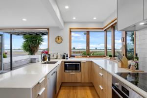 a large kitchen with white countertops and windows at Beachside Bliss - Redcliffs in Christchurch