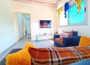Chic Appart Climatisé Wifi 1er Etage في لوميه: غرفة معيشة مع أريكة زرقاء وتلفزيون