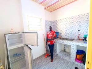 Chic Appart Climatisé Wifi 1er Etage في لوميه: رجل واقف في غرفه في مطبخ