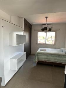 a white bedroom with a bed and a window at Apto aconchegante no Centro in Jaguarão