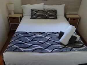 - un lit avec des draps et des oreillers en noir et blanc dans l'établissement Forster and Wallis Lake Motel, à Forster