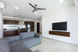La Poza Suites في إيسلا موخيريس: غرفة معيشة مع أريكة وتلفزيون بشاشة مسطحة