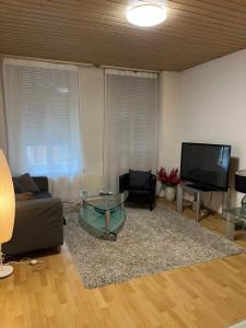 uma sala de estar com uma mesa de vidro e uma televisão em room service Joppich em St. Gallen