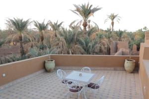 een tafel en stoelen op een balkon met palmbomen bij riad dar susan in Zagora