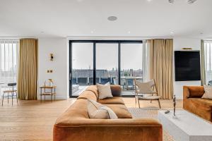 a living room with a brown couch and a large window at Modern King's Cross Apartments in London