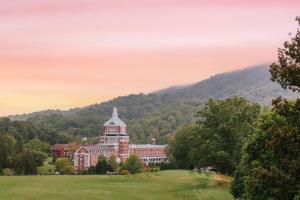 a large red building with a tower on a golf course at The Omni Homestead Resort in Hot Springs