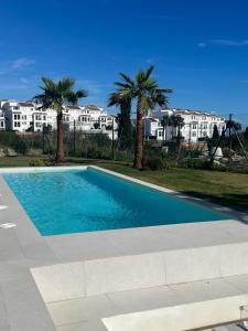 une piscine avec des palmiers et des bâtiments en arrière-plan dans l'établissement Luxury Villa in perfect location with sea views, à Castillo de Sabinillas