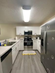 a kitchen with white cabinets and a stainless steel refrigerator at A Touch of Sunshine Ideal For Long Term Stays in Fayetteville